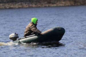 A man fishing from an inflatable boat